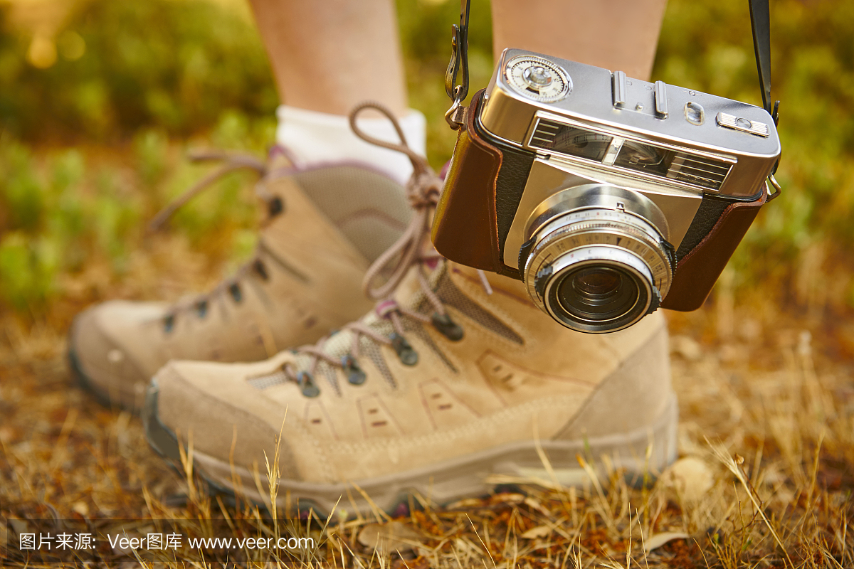 复古相机与徒步靴在地面上。旅行